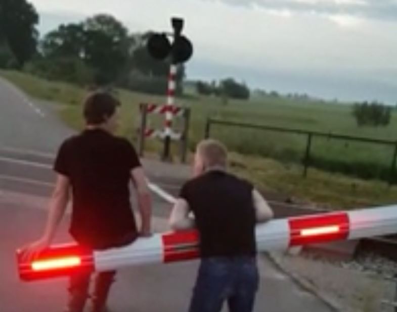 Still frame uit de video met de twee daders die een overwegboom misbruiken.